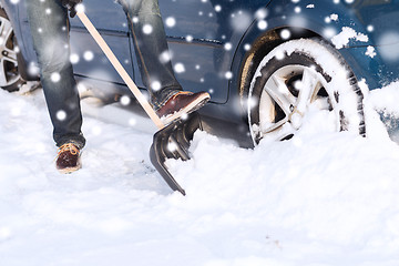 Image showing closeup of man digging snow with shovel near car