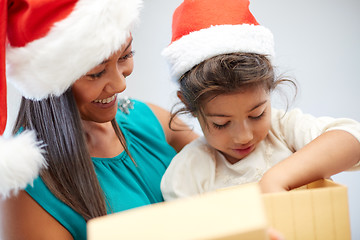 Image showing happy mother and child in santa hats with gift box