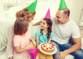 Image showing smiling family with two kids in hats with cake