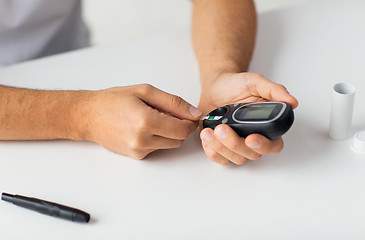 Image showing close up of man checking blood sugar by glucometer