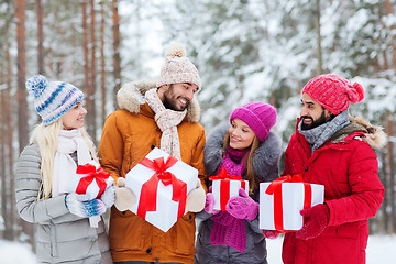 Image showing happy friends with gift boxes in winter forest