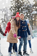 Image showing happy friends ice skating on rink outdoors