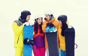 Image showing happy friends in helmets with snowboards talking