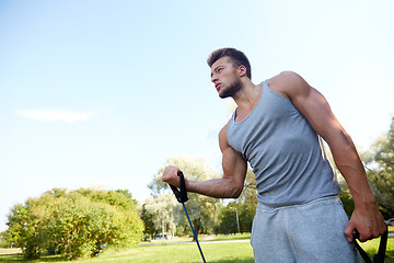 Image showing young man exercising with expander in summer park
