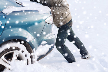 Image showing closeup of man pushing car stuck in snow