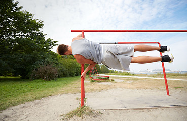 Image showing young man exercising on parallel bars outdoors