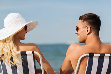 Image showing happy couple sunbathing in chairs on summer beach