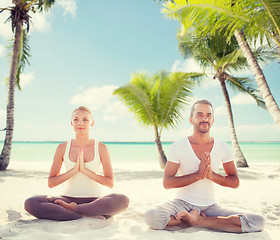 Image showing smiling couple meditating on tropical beach