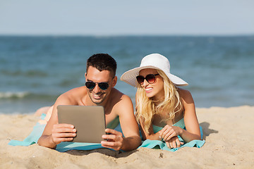 Image showing happy couple with tablet pc sunbathing on beach