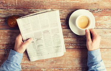 Image showing close up of male hands with newspaper and coffee