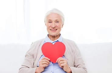 Image showing happy smiling senior woman with red heart at home