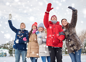 Image showing happy friends waving hands on ice rink outdoors