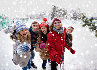 Image showing happy friends with smartphone on ice skating rink