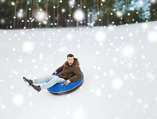 Image showing happy young man sliding down on snow tube