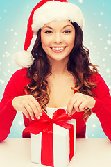 Image showing smiling woman in santa helper hat with gift box