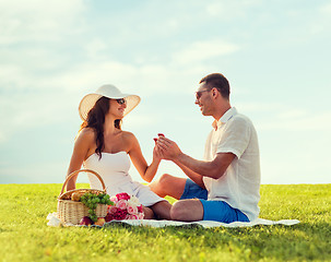 Image showing smiling couple with small red gift box on picnic