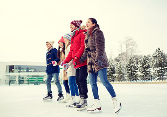 Image showing happy friends ice skating on rink outdoors