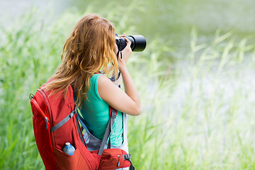 Image showing young woman with backpack and camera outdoors