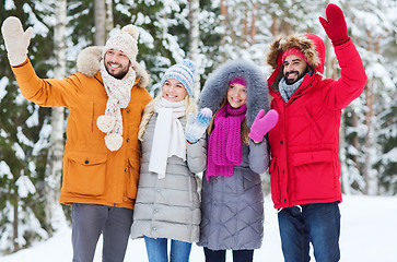 Image showing group of friends waving hands in winter forest