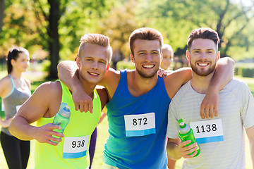 Image showing happy friends with racing badge numbers and water