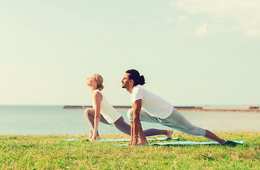 Image showing smiling couple making yoga exercises outdoors