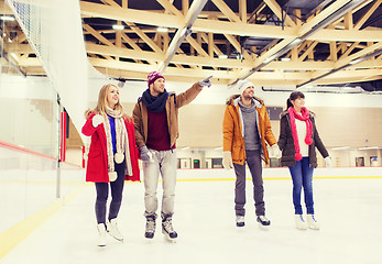 Image showing happy friends pointing finger on skating rink