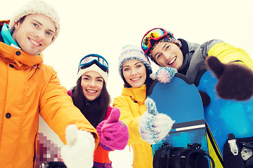 Image showing happy friends with snowboards showing thumbs up