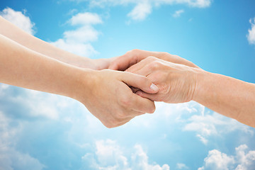 Image showing close up of senior and young woman holding hands