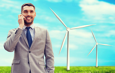 Image showing smiling businessman with smartphone outdoors