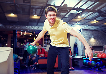 Image showing happy young man throwing ball in bowling club