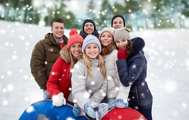 Image showing smiling friends with snow tubes and selfie stick