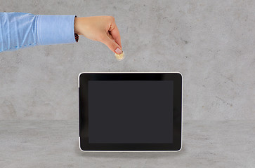 Image showing close up of hand putting coin into tablet pc