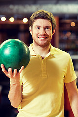 Image showing happy young man holding ball in bowling club