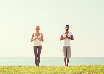 Image showing smiling couple making yoga exercises outdoors