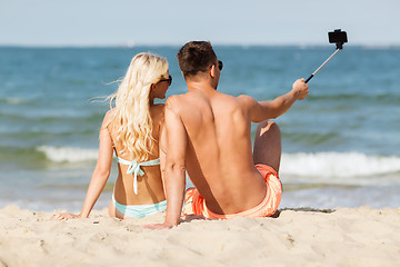 Image showing happy couple in swimwear sitting on summer beach