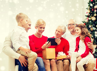 Image showing smiling family with tablet pc and gift box at home