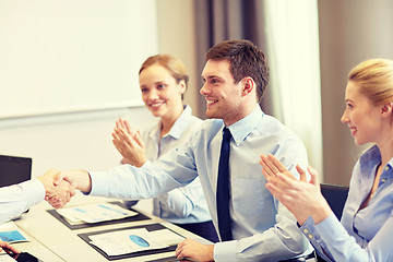 Image showing smiling business team shaking hands in office