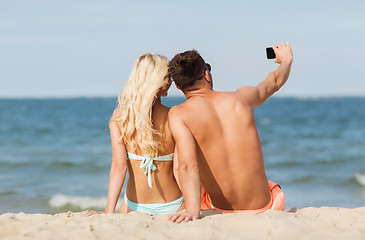 Image showing happy couple in swimwear sitting on summer beach