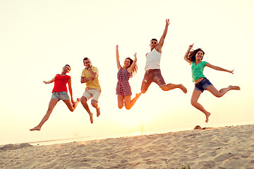 Image showing smiling friends dancing and jumping on beach