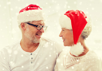 Image showing happy senior couple in santa helper hats at home