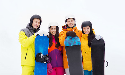 Image showing happy friends in helmets with snowboards outdoors