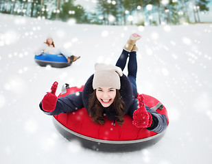 Image showing group of happy friends sliding down on snow tubes