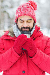 Image showing smiling young man with cup in winter forest