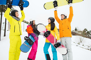 Image showing happy friends in helmets with snowboards outdoors