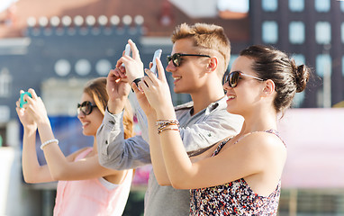 Image showing smiling friends with smartphone taking picture