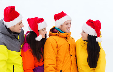 Image showing happy friends in santa hats and ski suits outdoors