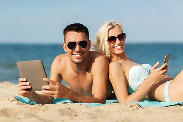 Image showing happy couple with tablet pc sunbathing on beach