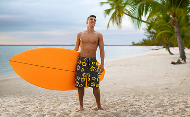 Image showing smiling young man with surfboard on summer beach