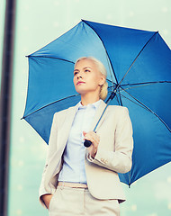 Image showing young serious businesswoman with umbrella outdoors