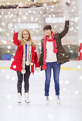 Image showing happy girls friends waving hands on skating rink